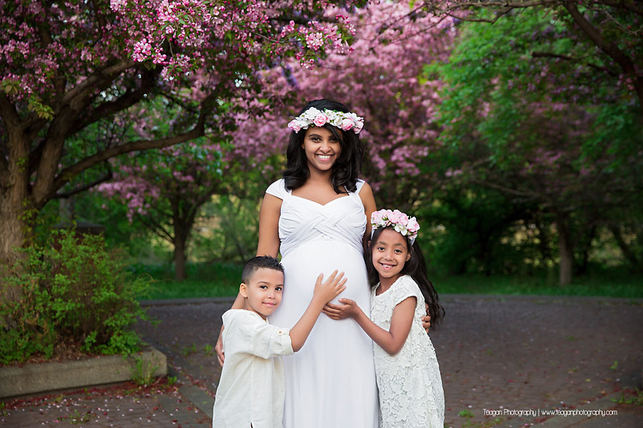 A pregnant mother poses with her two children underneath a blossoming crab apple tree in the Edmonton River valley