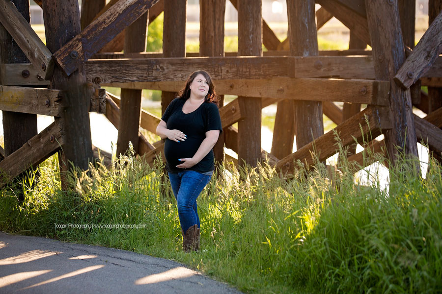 A mother's hair golows from the summer in during a maternity photography session at St Albert's Red Willo wPark by the train trestle bridge