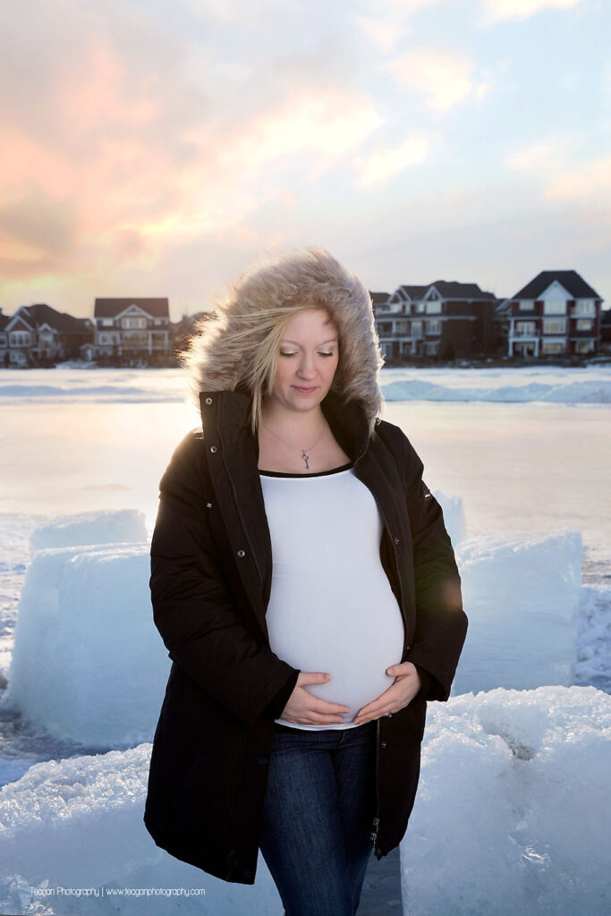 Outdoor winter pregnancy photos featuring a couple in front of frozen Lake Summerside landscape