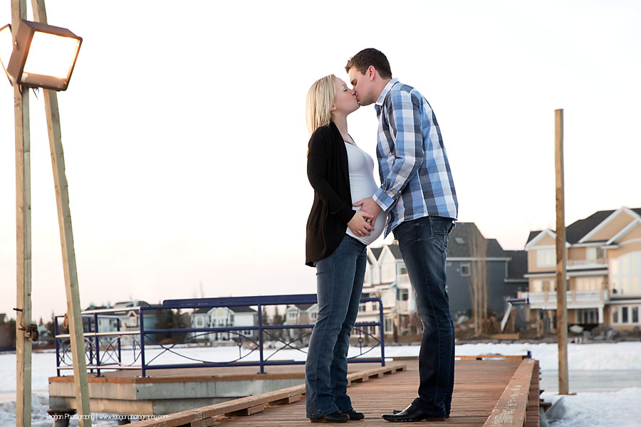YEG maternity photographer capturing couple standing by large blocks of carved lake ice at sunset
