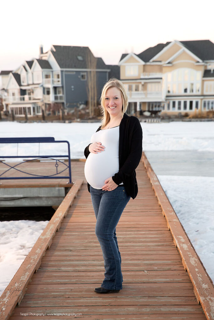 YEG maternity photographer capturing couple standing by large blocks of carved lake ice at sunset