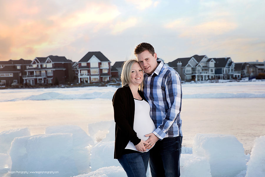 YEG maternity photographer capturing couple standing by large blocks of carved lake ice at sunset