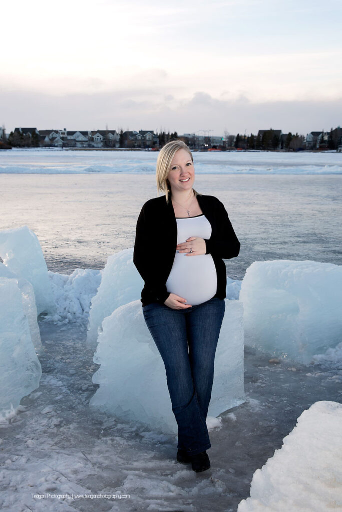 YEG maternity photographer capturing couple standing by large blocks of carved lake ice at sunset