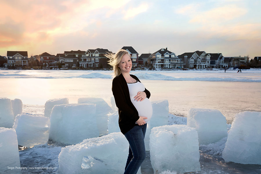 YEG maternity photographer capturing couple standing by large blocks of carved lake ice at sunset