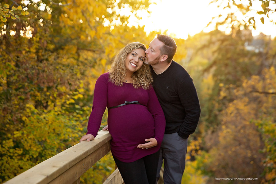 Close up of baby bump with a crisp running stream and colorful autumn leaves in the background in Edmonton
